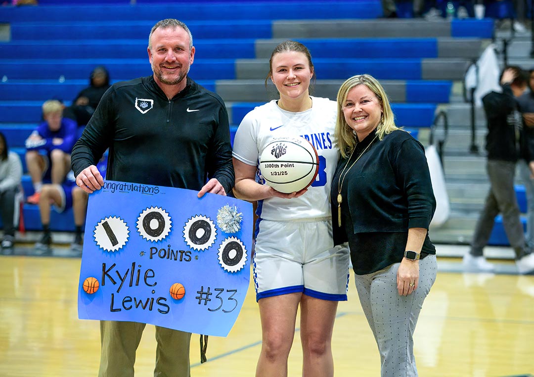Polk County assistant coach Billy Alm and head coach Brandy Alm flank senior Kylie Lewis, who scored her 1,000th career point on Friday
